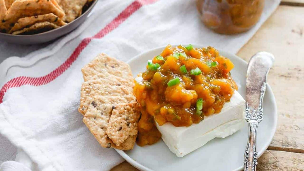 Jalapeño mango jam in a glass jar with a spoon.