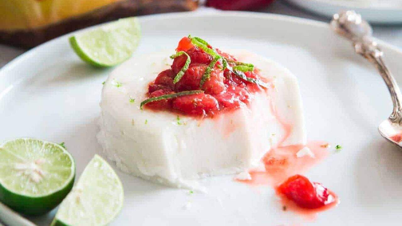 Key lime coconut panna cotta on a white plate topped with a strawberry lime compote.