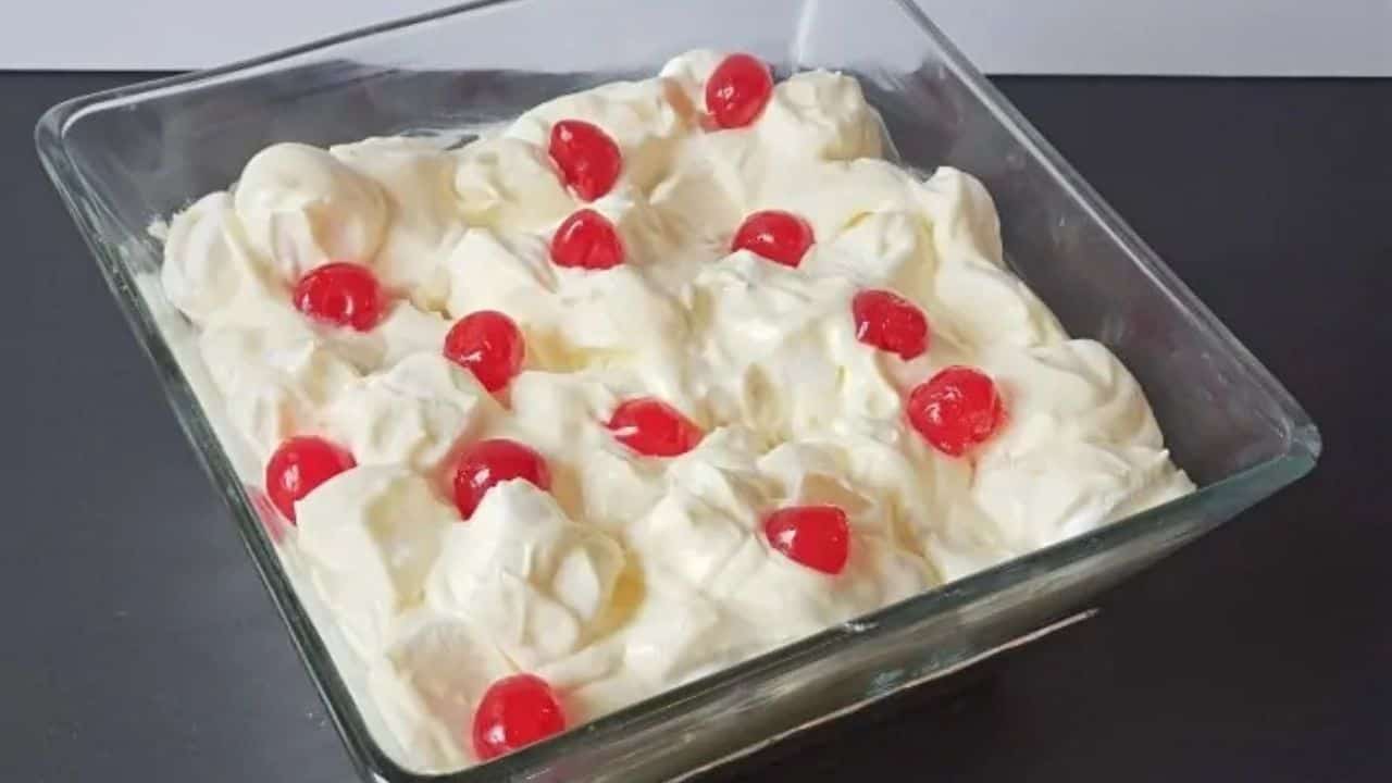 Bowl of marguerite salad topped with cherries on a black counter.