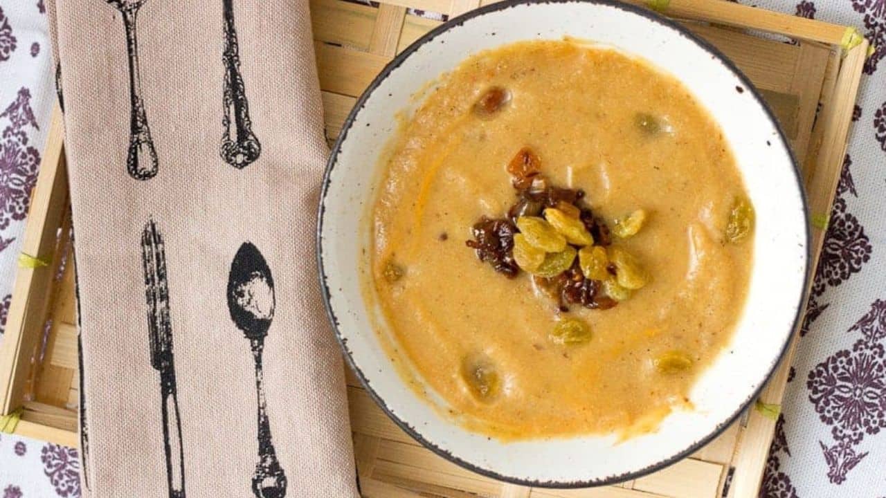 A bowl of soup is sitting on a wooden tray.
