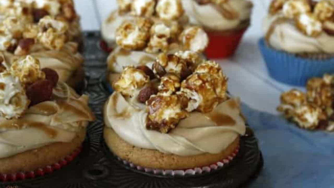 A tray of cupcakes topped with caramel and popcorn.