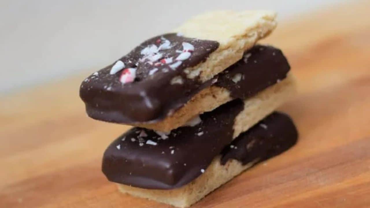 Image shows a stack of four Peppermint Shortbread Cookies on a wooden table.