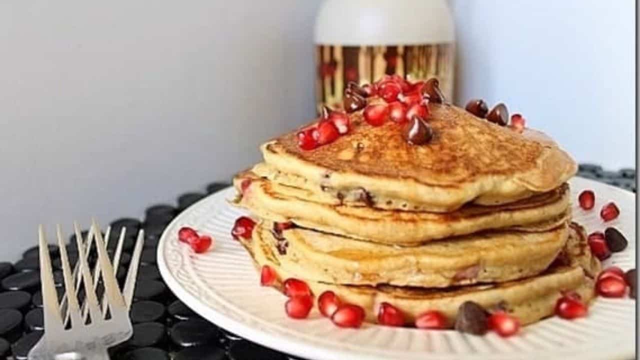 A stack of pancakes with pomegranate and chocolate chips.