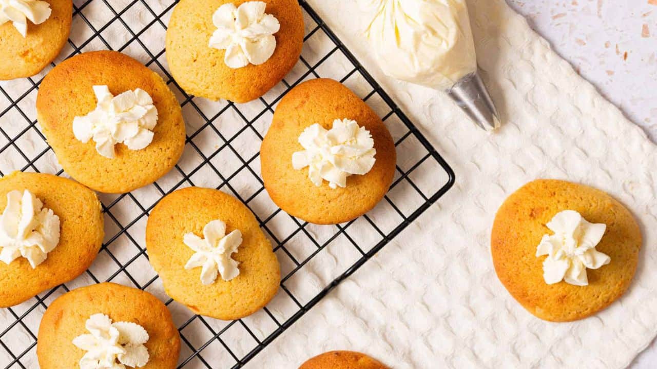 An overhead image of pumpkin pie cookies with whipped cream on top cooled on a wire rack.