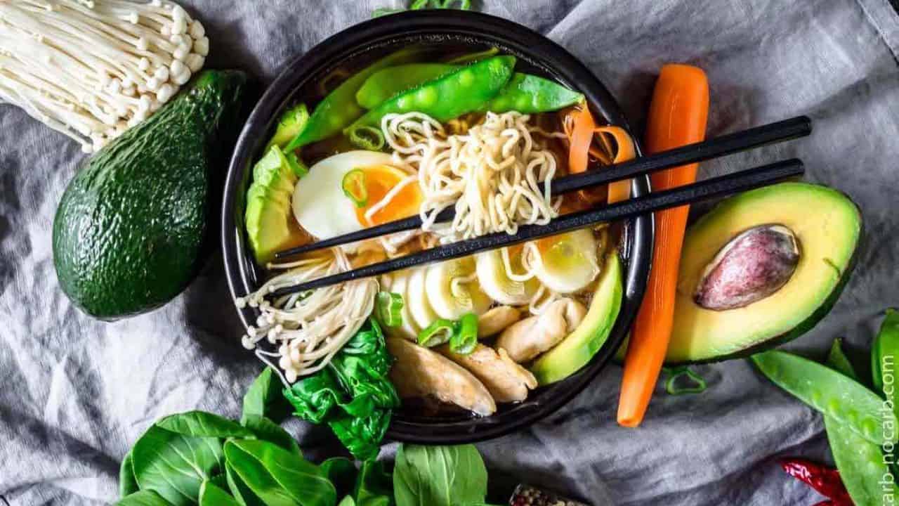 Keto Ramen Chicken Noodles in a black bowl with various vegetables and boiled egg.