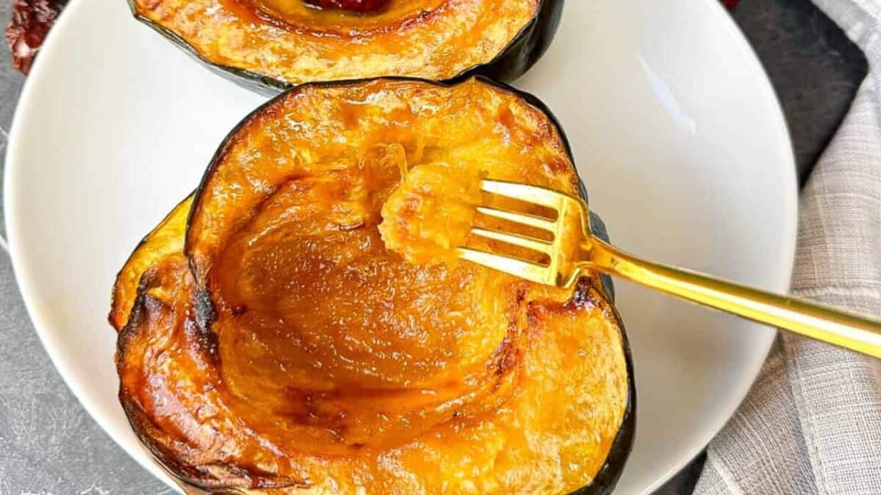 Sweet and tender air fryer acorn squash topped with brown sugar on a plate with a golden fork.