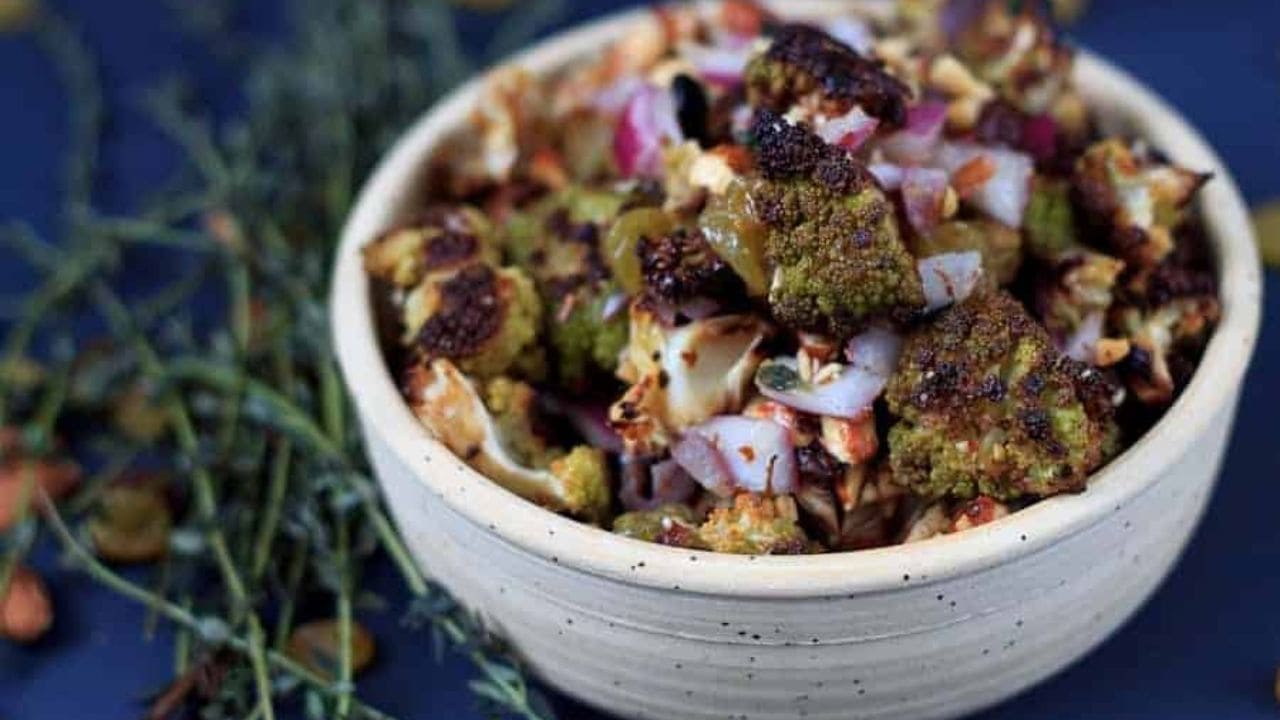 A bowl of roasted cauliflower with onions and sprigs of thyme.