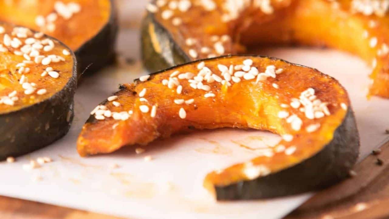 Close-up of baked kabocha squash slices seasoned with sesame seeds.