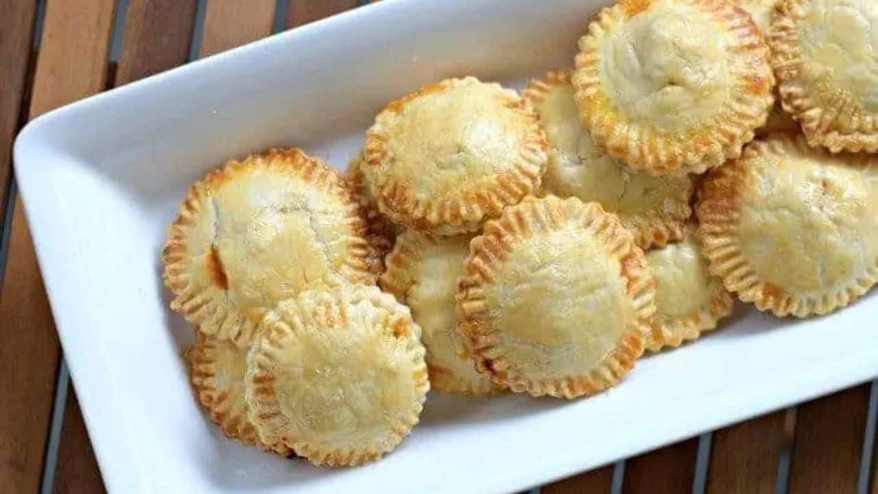 Image shows an overhead shot of puff pastry Chicken Empanadas on a white tray.