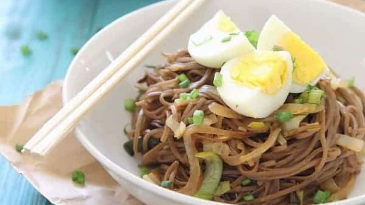 Soba noodles in a bowl with green onions, leeks and hard boiled egg.