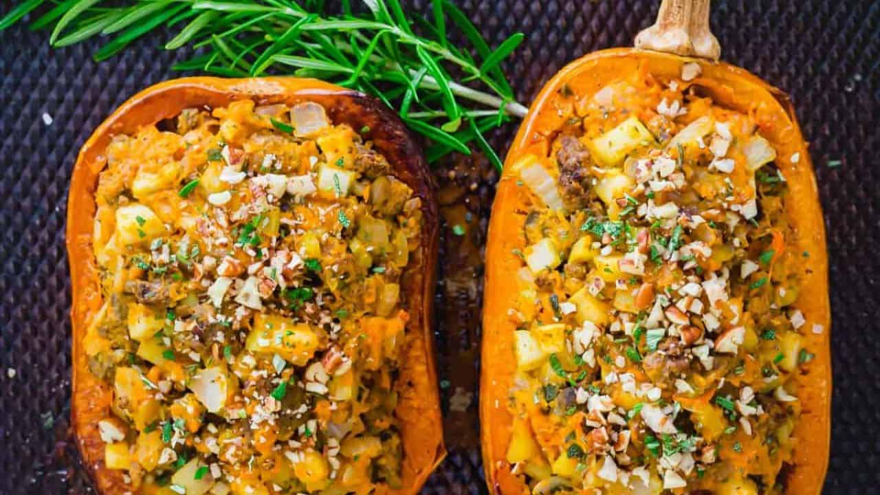 Two stuffed honeynut squash halves on a wooden table.