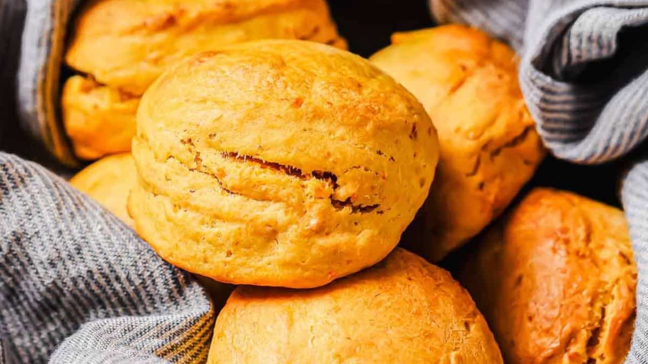 A close-up of several golden brown biscuits nestled in a blue and white striped cloth.