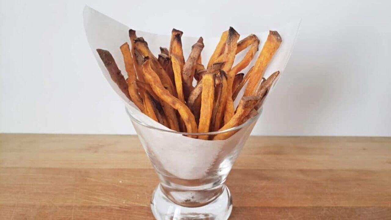 Image shows a glass filled with Sweet Potato Fries.
