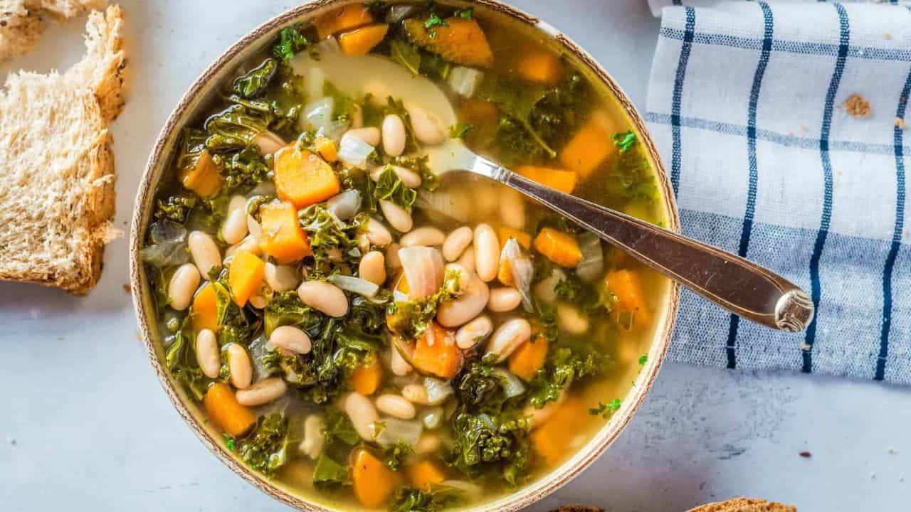 An overhead view of the Tuscan bean soup placed on a serving dish with a spoon on the side.
