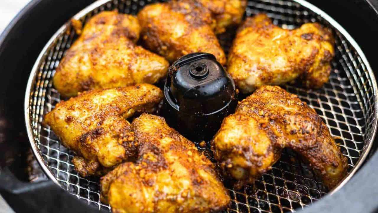 Chicken wings cooking in an air fryer.
