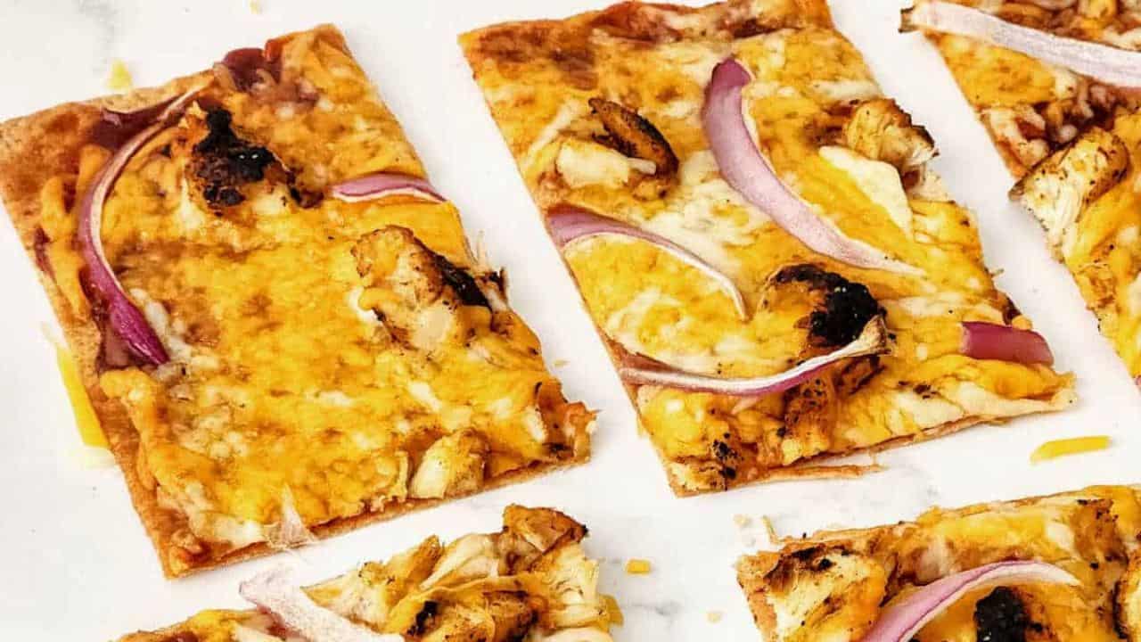 Grilled chicken flatbread pizzas on a marble countertop.