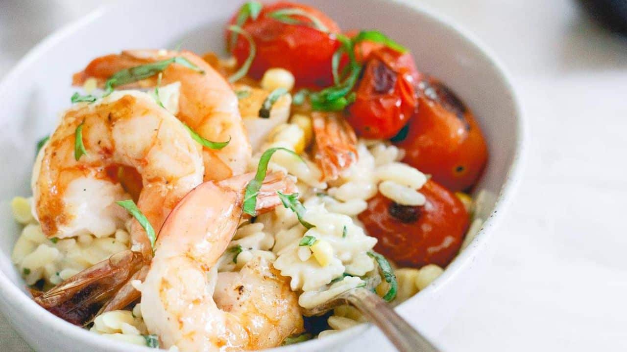 Brown butter shrimp and orzo served with burst cherry tomatoes in a bowl.