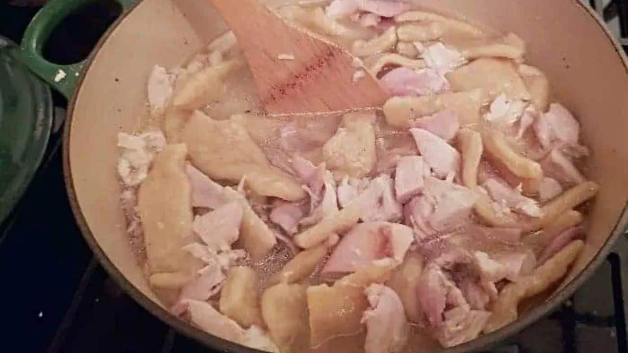 Image shows Chicken and dumplings on a spoon with more in the backgroumd.