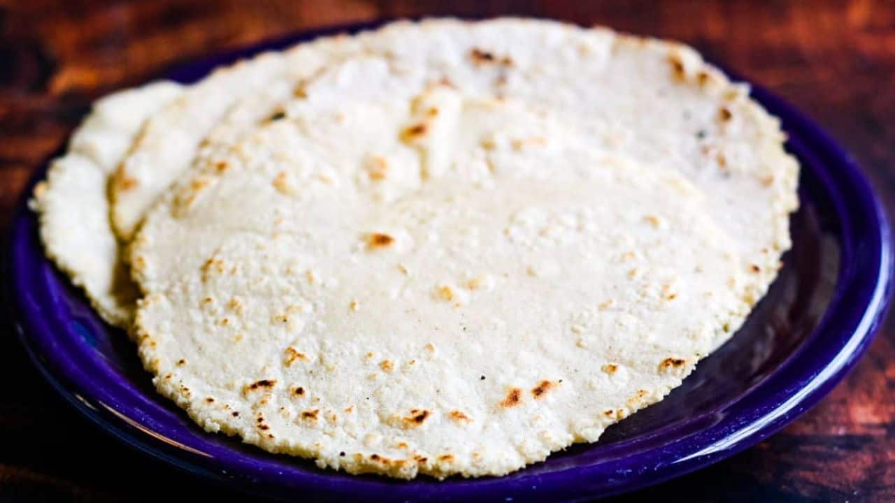 Stack of corn tortillas on a purple plate.