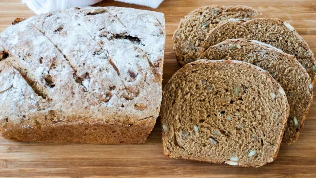 A sliced loaf of Danish rye bread in a wooden board.