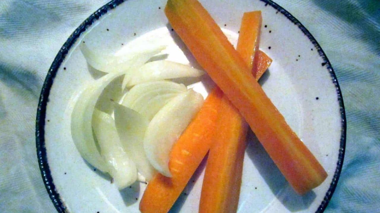 A plate with sliced vegetables: orange carrot sticks and white onion slices, straight from Grandpa's recipes.