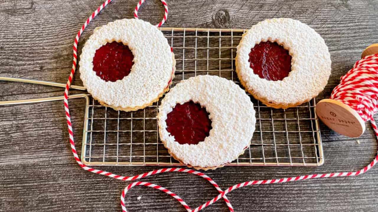 Three linzer cookies in a cooling tray.