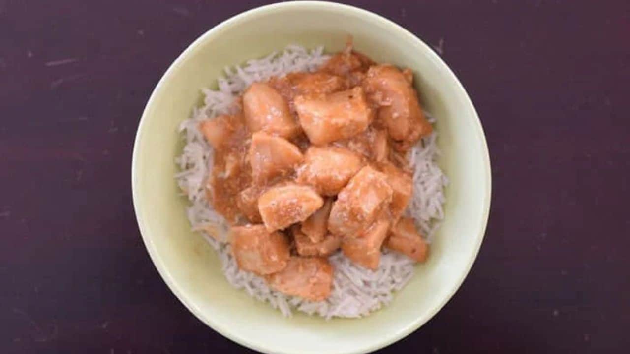 Overhead shot of honey bourbon chicken in a bowl on a black counter.