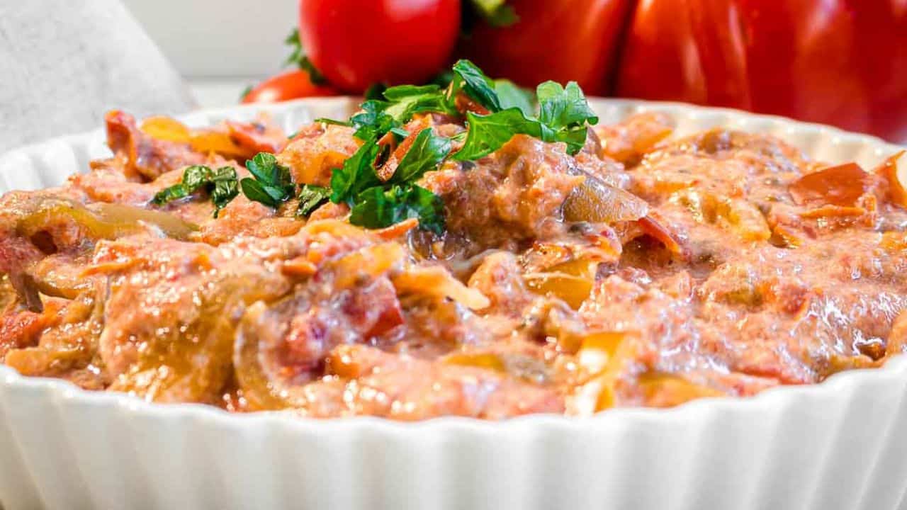 A girl holding a big casserole filled with vegetable stew.