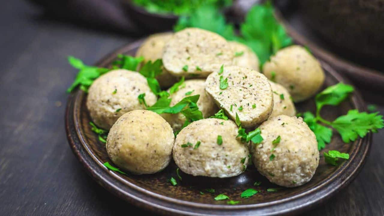 A plate of several seasoned dumplings garnished with fresh herbs.