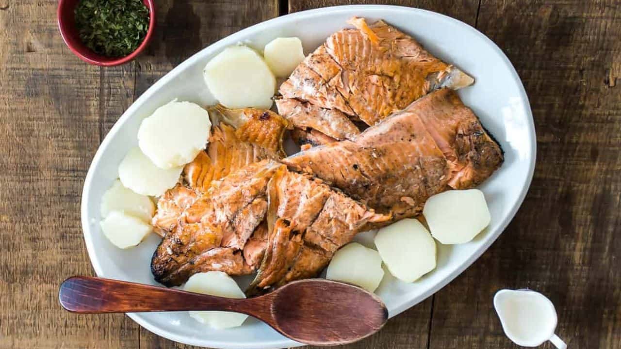 Overhead view of fire-grilled salmon in white plate.