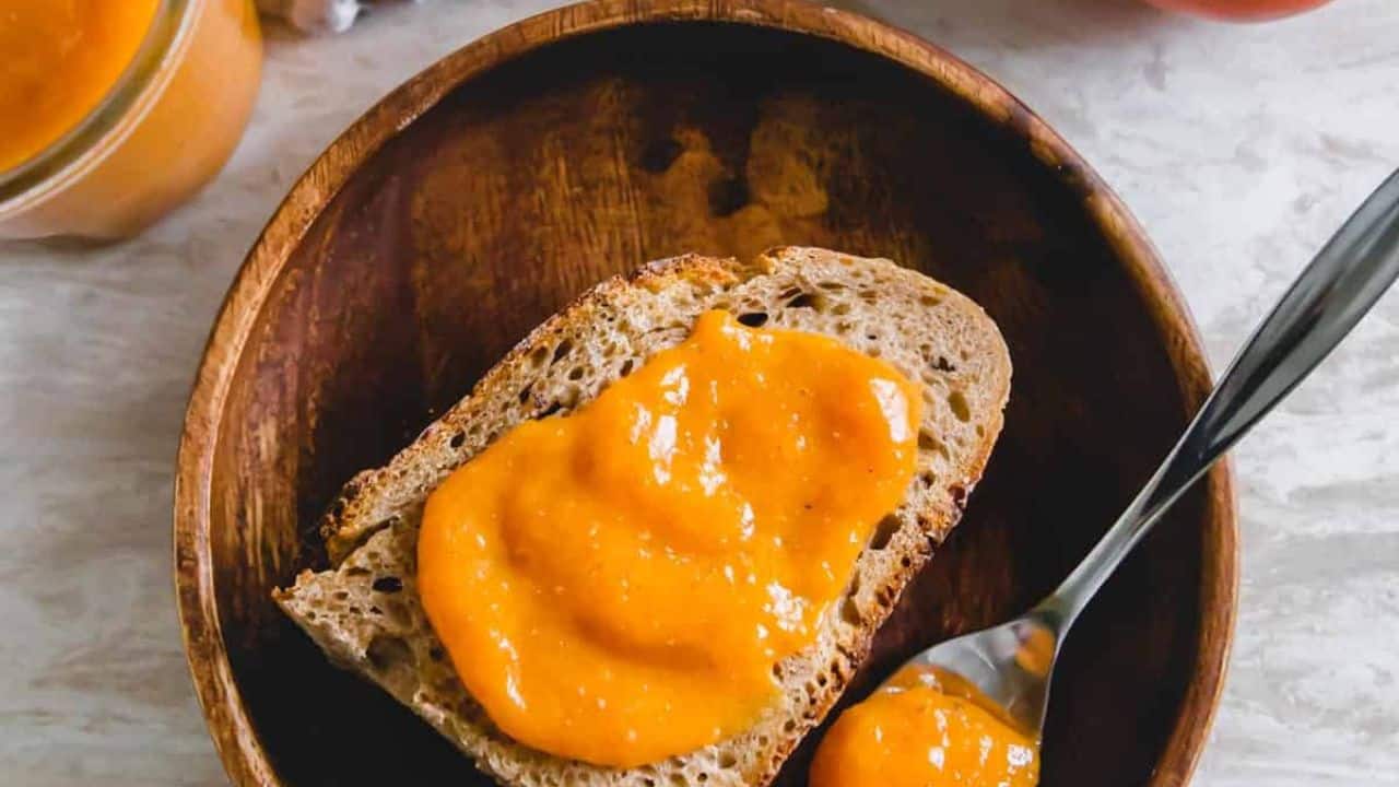Two jars of persimmon jam on a white plate.