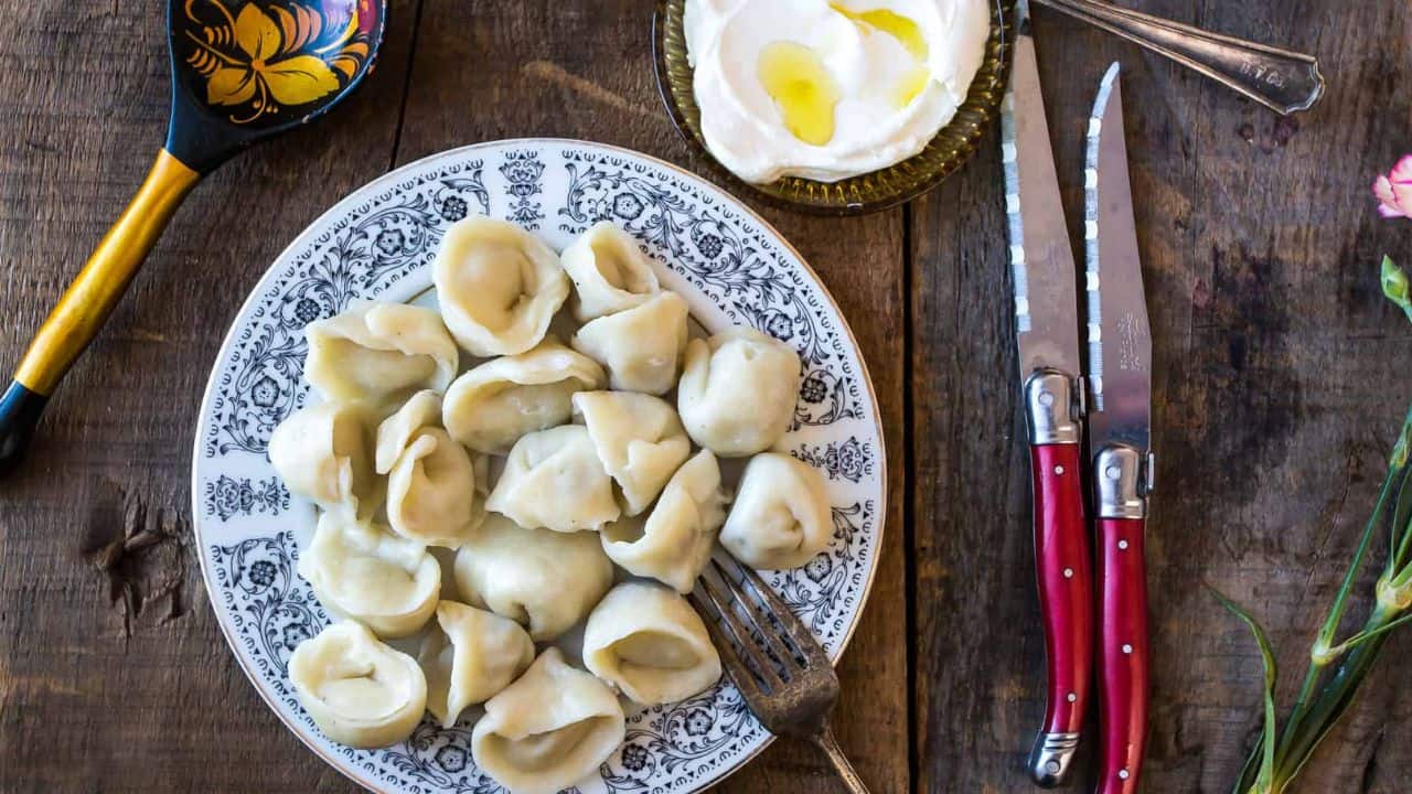 A plate of dumplings and assorted dishes arranged on a rustic wooden table.