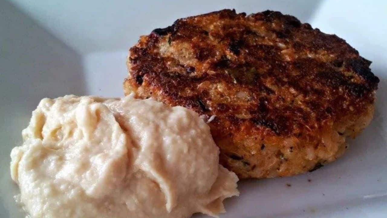 Image shows a quinoa burger patty next to a dollop of creamy roasted parsnip puree on a white plate.