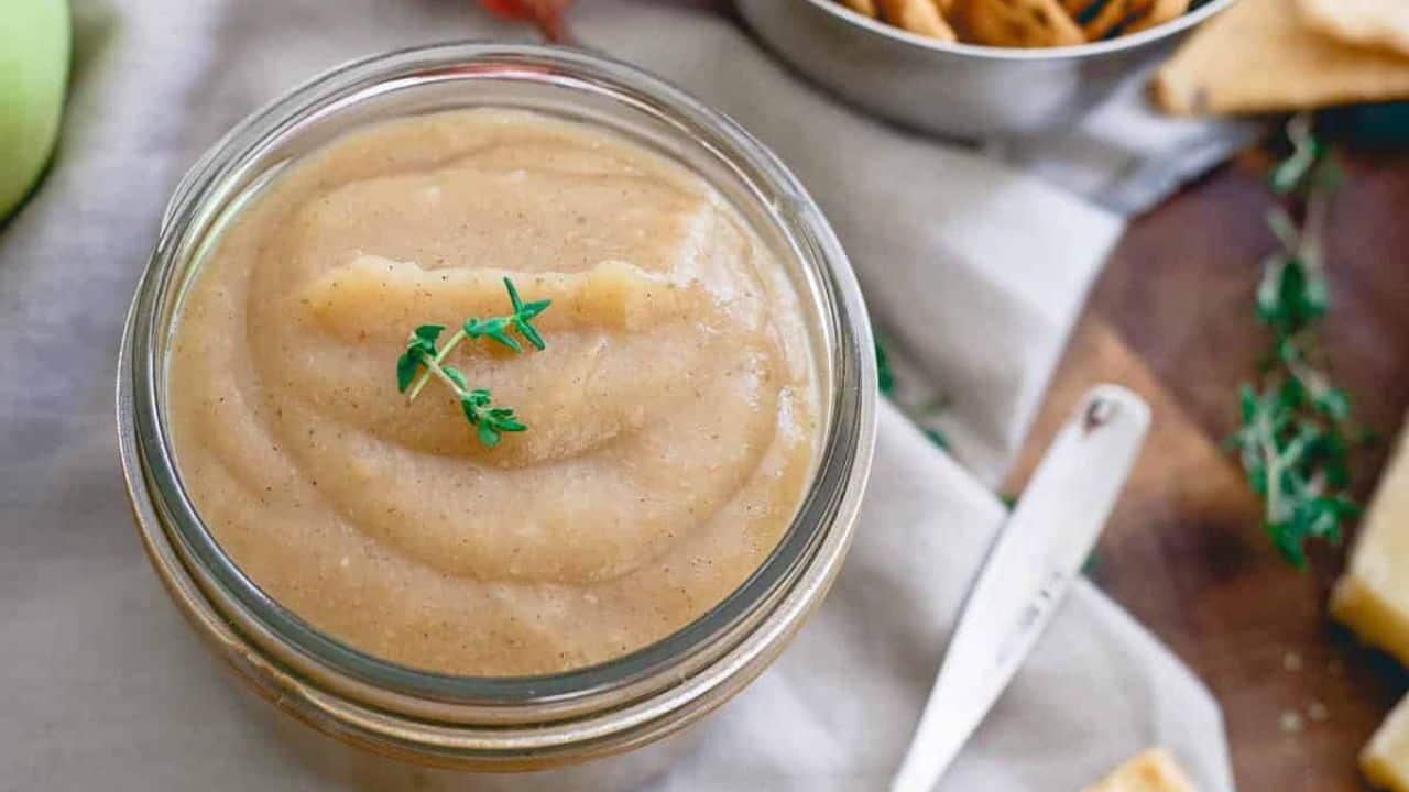 Apple thyme butter in a glass jar garnished with thyme leaves.