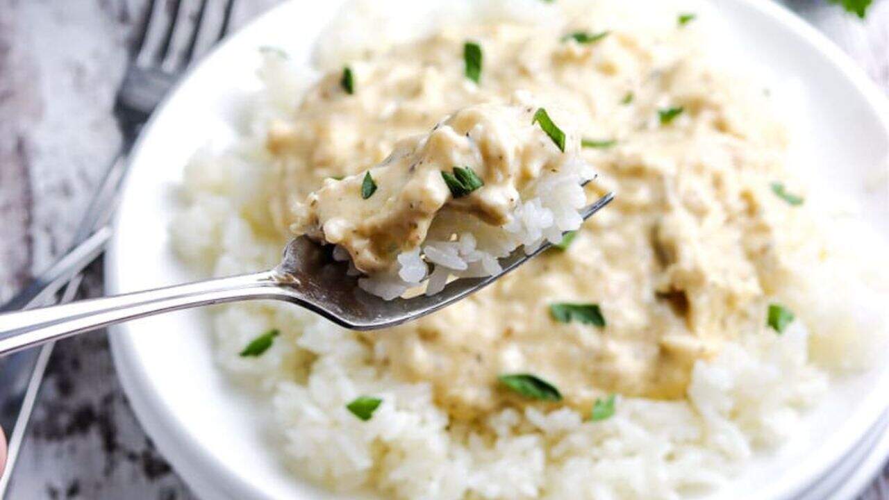 Slow Cooker Creamy Chicken on a white plate on rice topped with parsley.