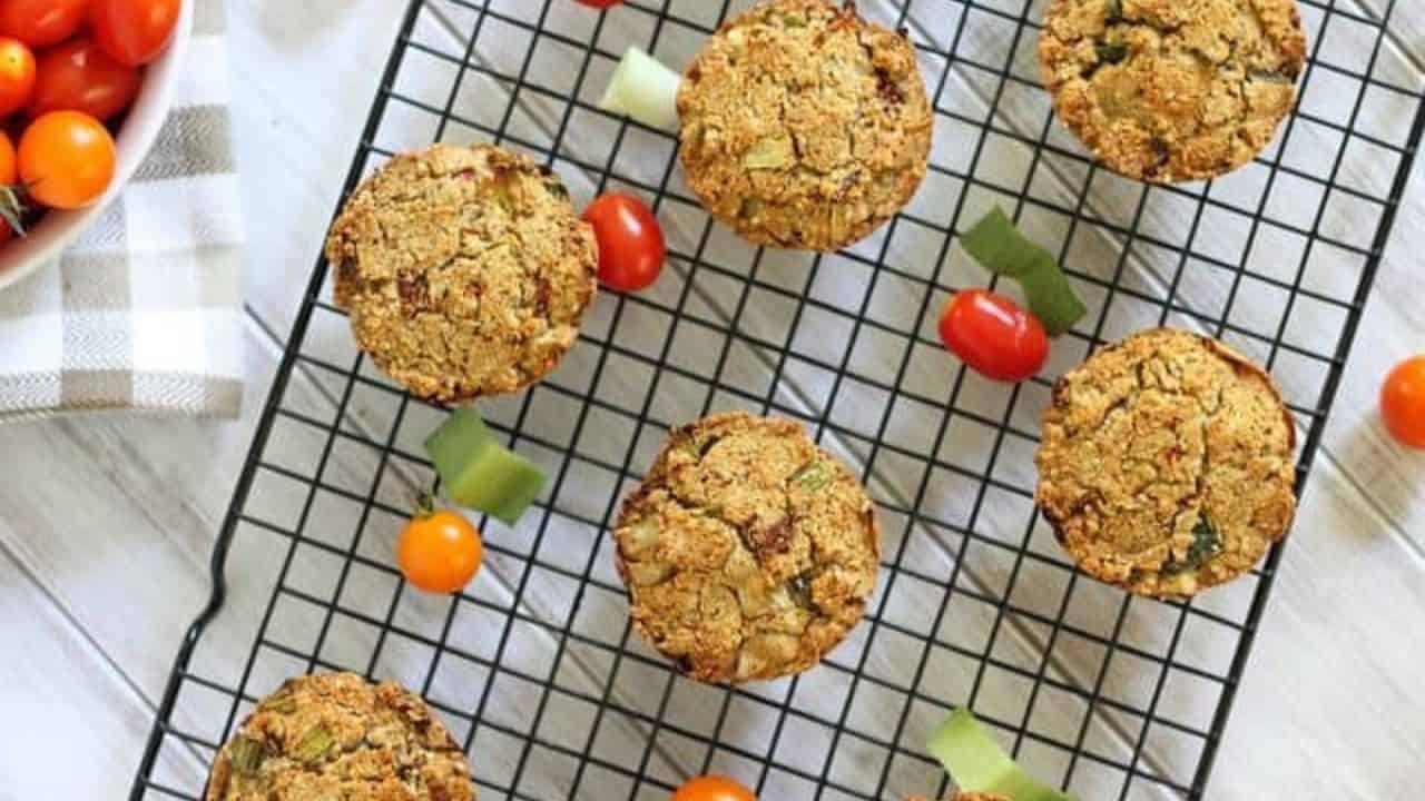 Sun-dried tomato leek muffins on a brown checkered kitchen towel.
