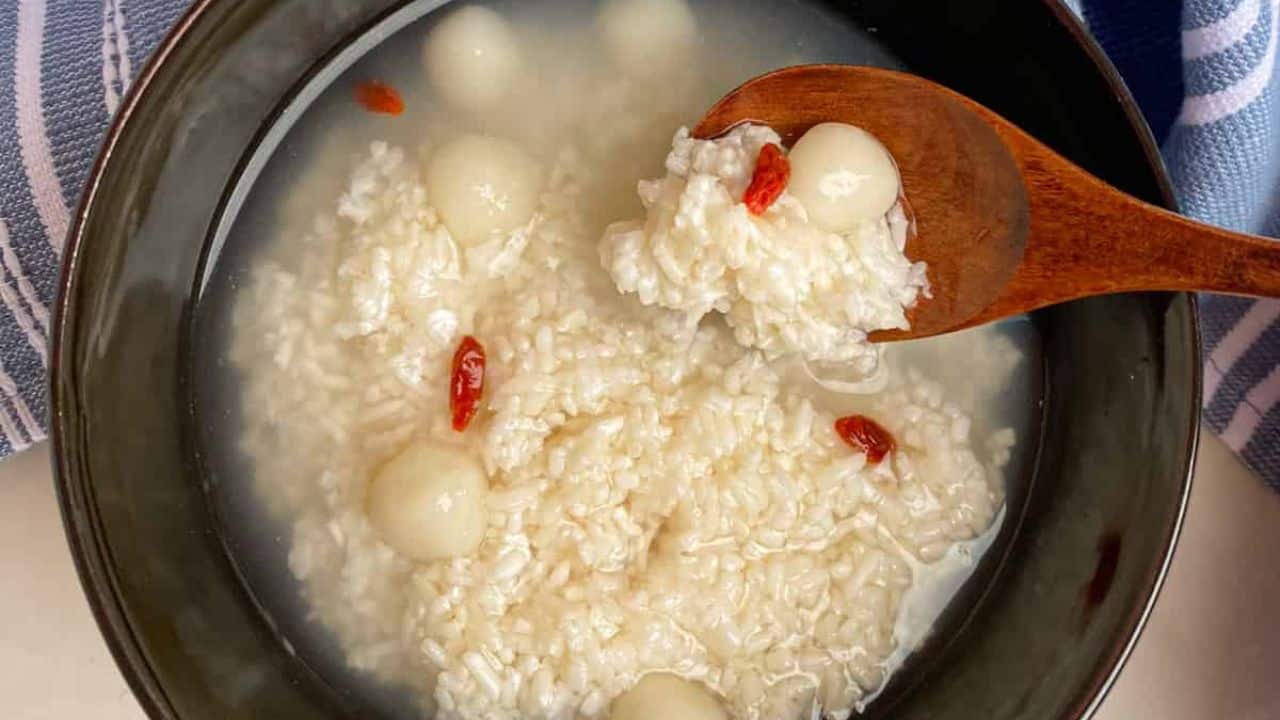 Sweet and mildly tangy fermented rice dessert in a black bowk with a wooden spoon.