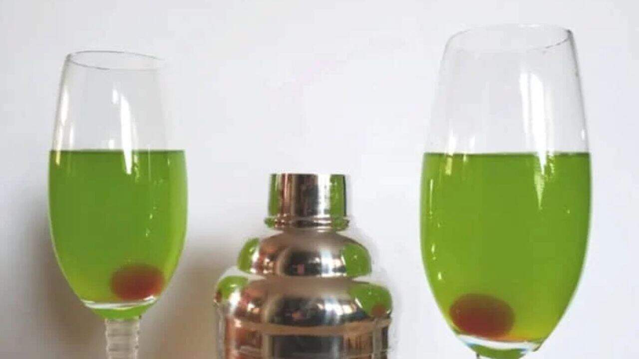 Image shows two flutes with a sweet and sour cocktail in them and a martini shaker between them.