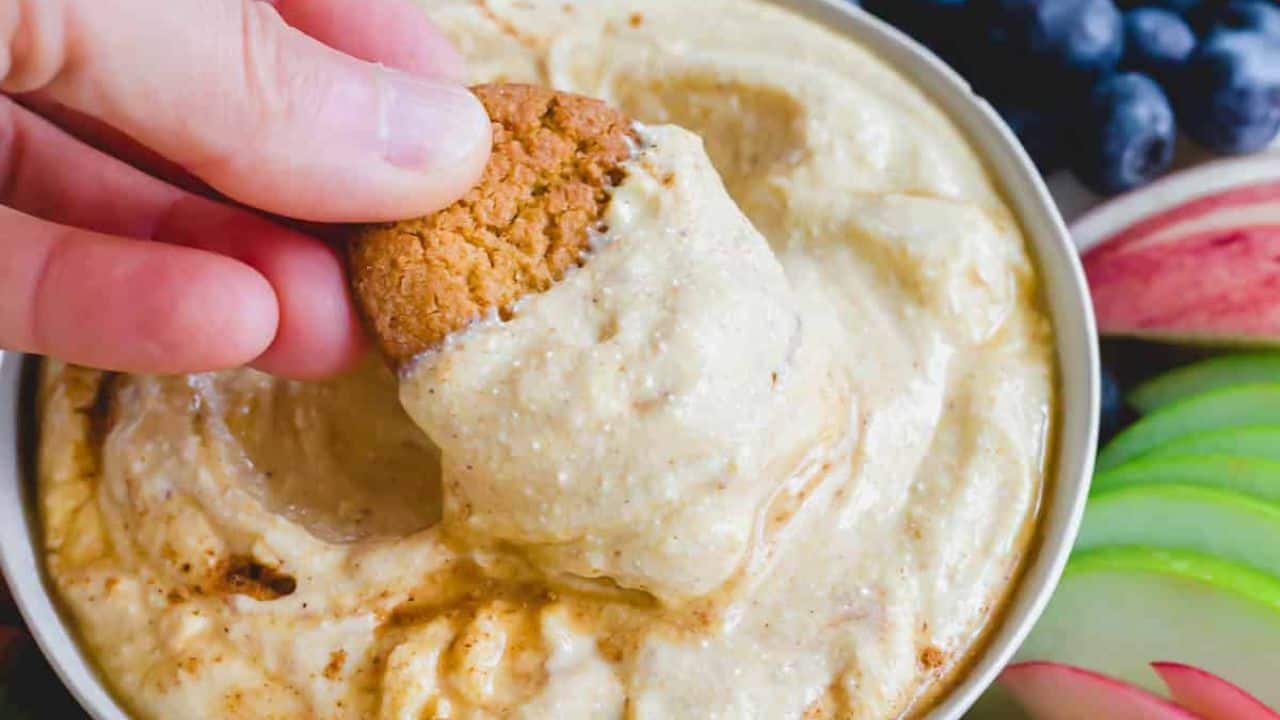 Whipped pumpkin ricotta dip on a wooden tray with cookies, walnuts and fruit.