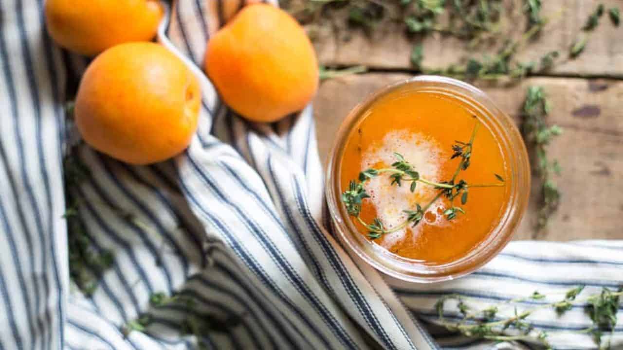 Overhead of apricot jam with apricots and thyme.