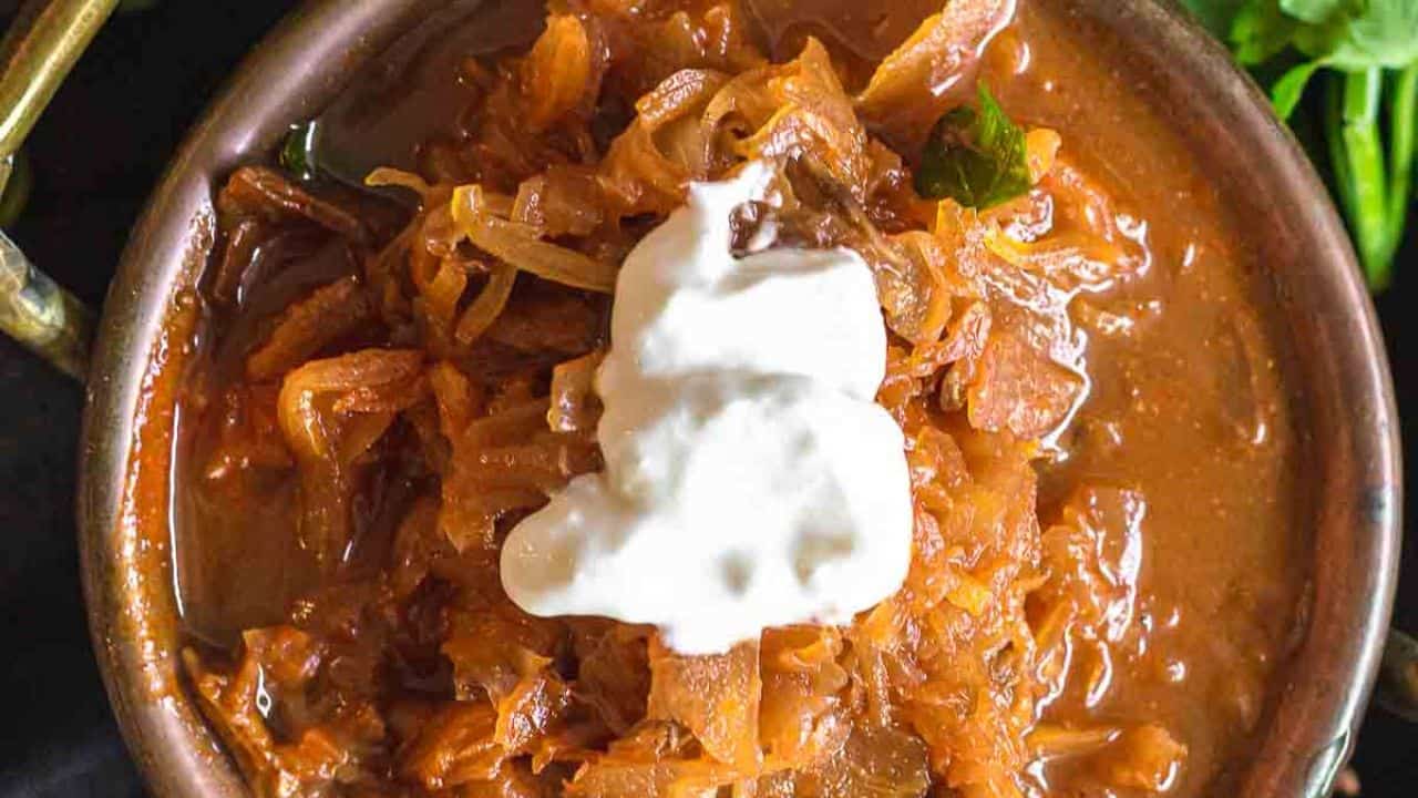 Sauerkraut Soup inside soup bowl with dollop of sour cream.