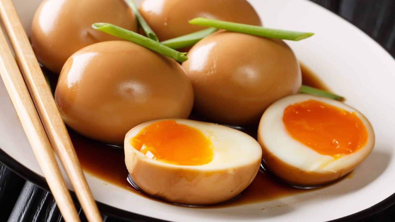 Soy sauce eggs on a white plate garnished with scallions.
