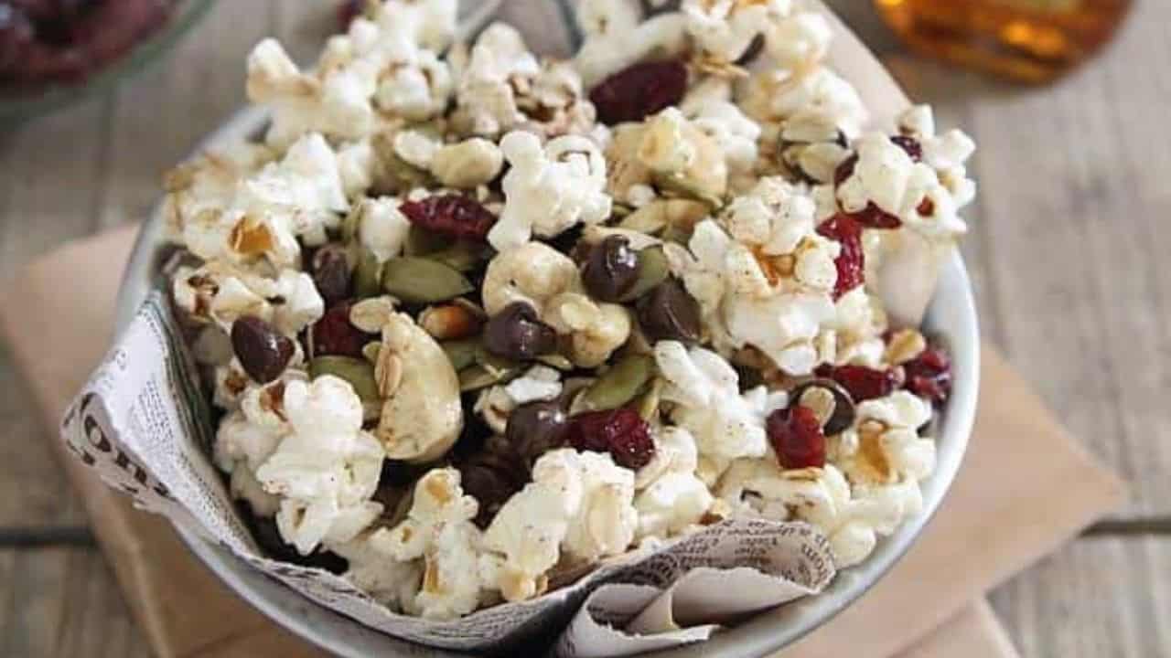 Trail mix popcorn in a bowl lined with newspaper.