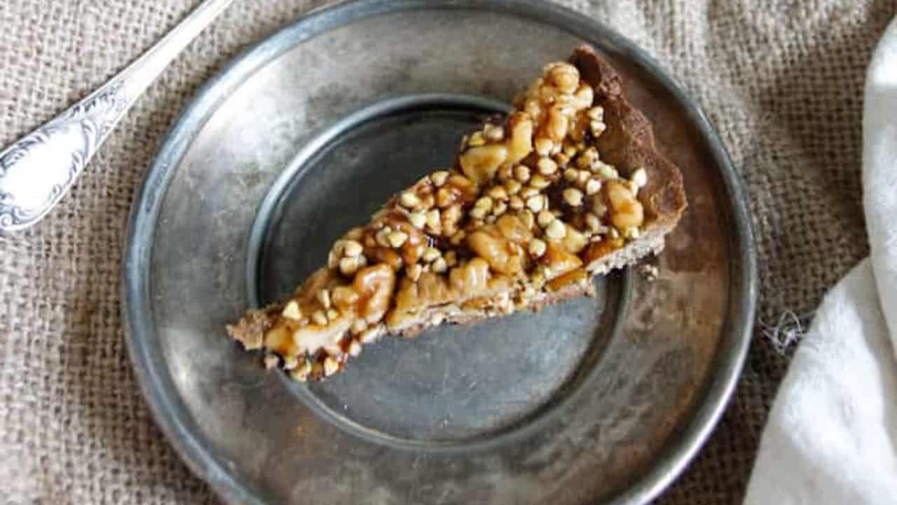 A walnut tart on a wooden cutting board with sprigs of thyme.