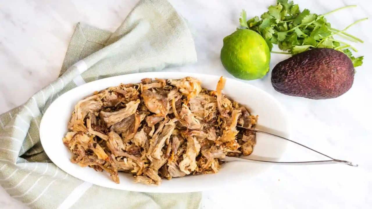 Al Pastor Carnitas in a white bowl with tongs.