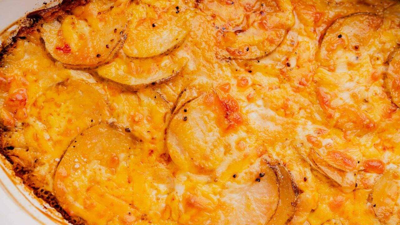 Close-up of baked cheesy potato gratin with golden-brown edges and slices of potato covered in melted cheese.