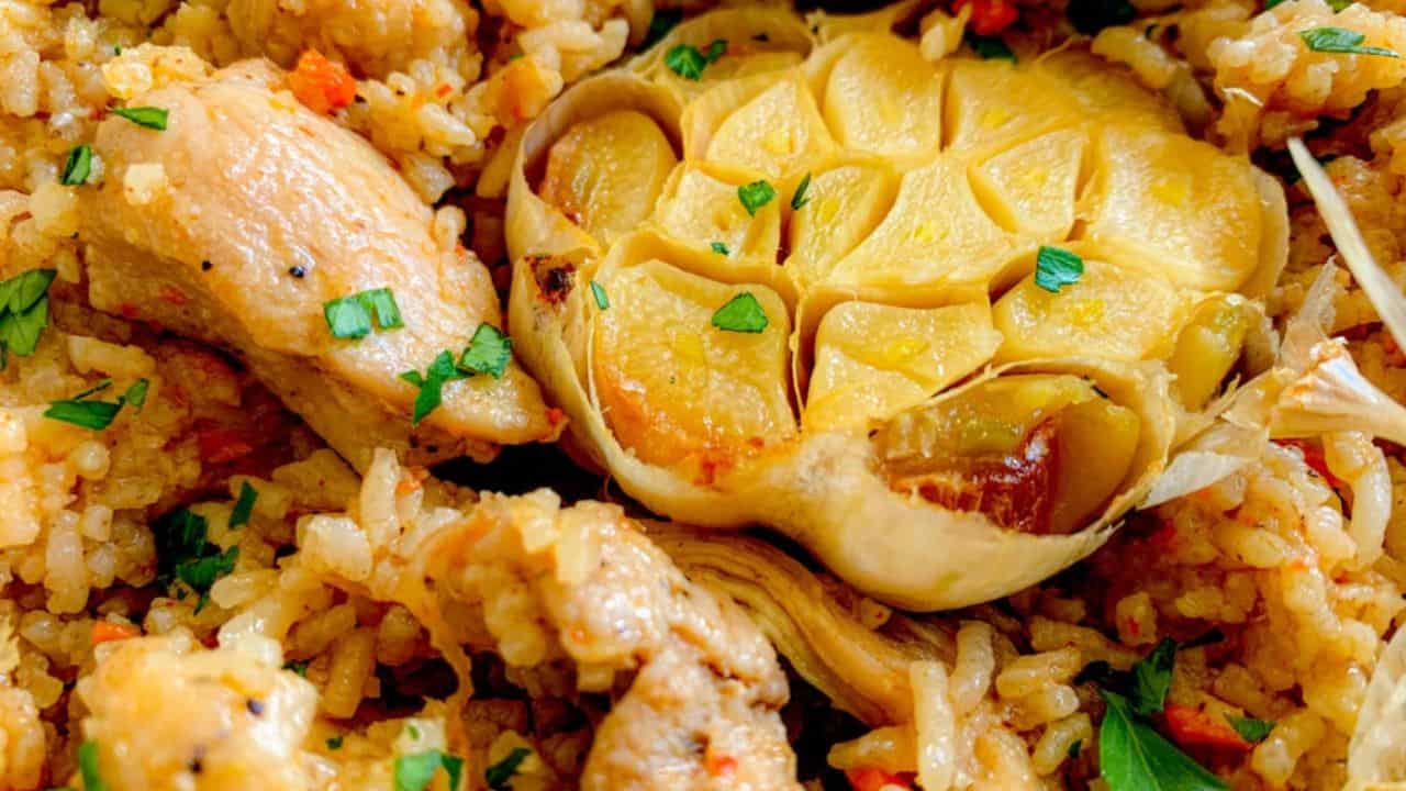 A Dutch oven filled with chicken and rice pilaf with garlic and spices.
