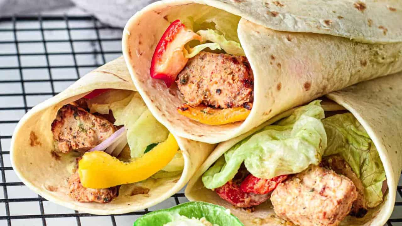 Low angle shot of 3 filled chicken tikka wraps.