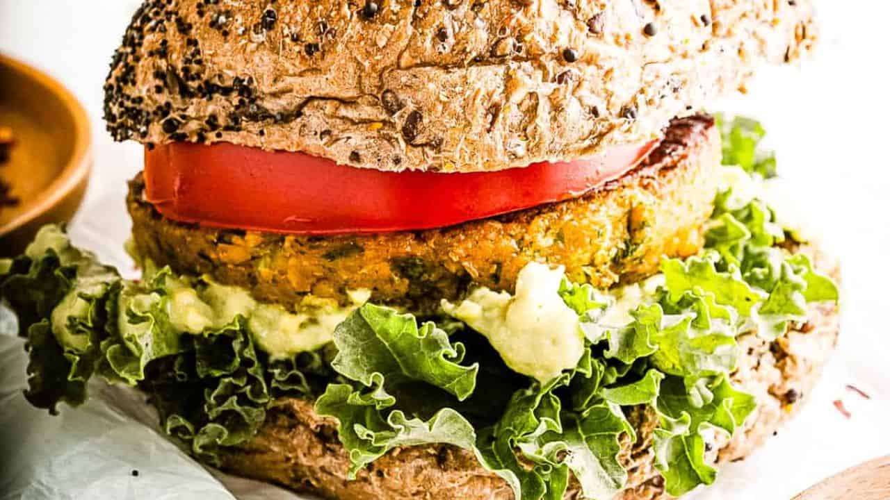 Low angle shot of 2 chickpea burgers on seeded buns with all the fixings.