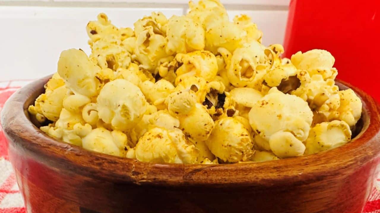 A bowl of popcorn on a red and white checkered tablecloth.